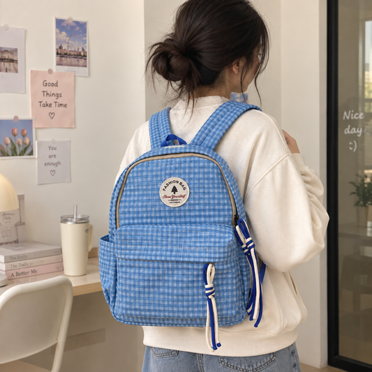 Cream plaid backpack with brown straps, front pocket and knotted zip pulls.