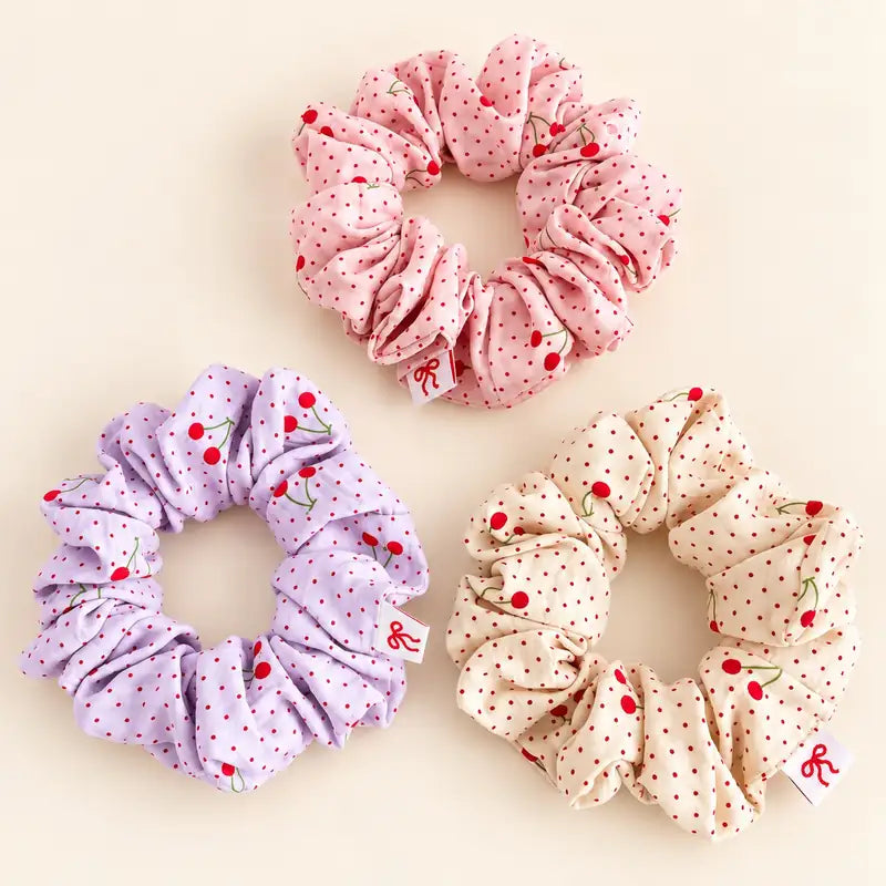 Cute cherry polka dot hair scrunchies in pastel pink, purple and cream with soft ruffled fabric.