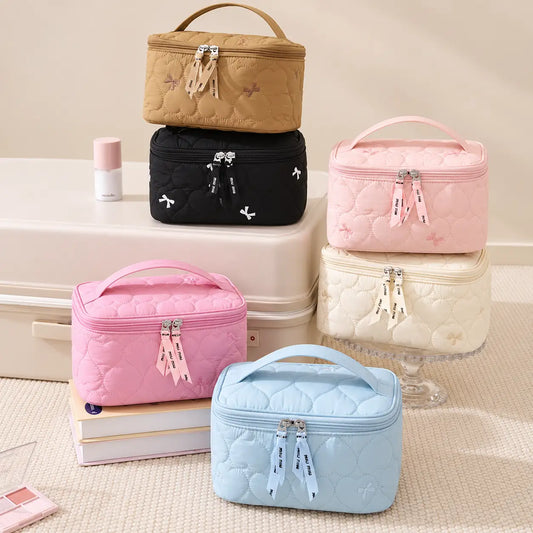 Kawaii Bow Cosmetic Bag with heart-quilted design, cute bow embroidery, double zipper closure, and carry handle, available in six colours. Size: 21 × 13.5 × 12 cm.