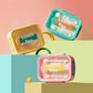  Pastel bento lunch box with transparent lid, built-in cutlery, carry handle, and secure side locks.