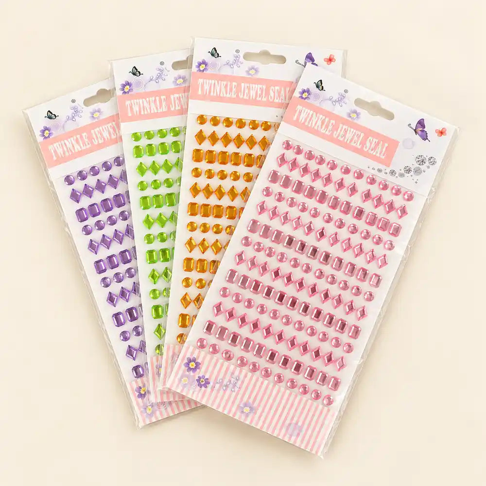 Four packages of Twinkle Jewel Seal rhinestone stickers arranged in a fan shape on a light beige background. The packages contain rhinestones in purple, green, orange, and pink, with pink striped borders at the bottom of each card.
